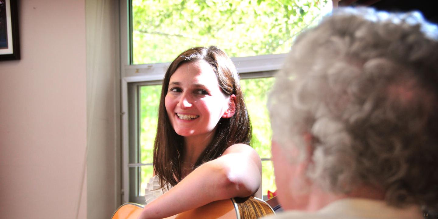 Music therapy student playing guitar for a senior